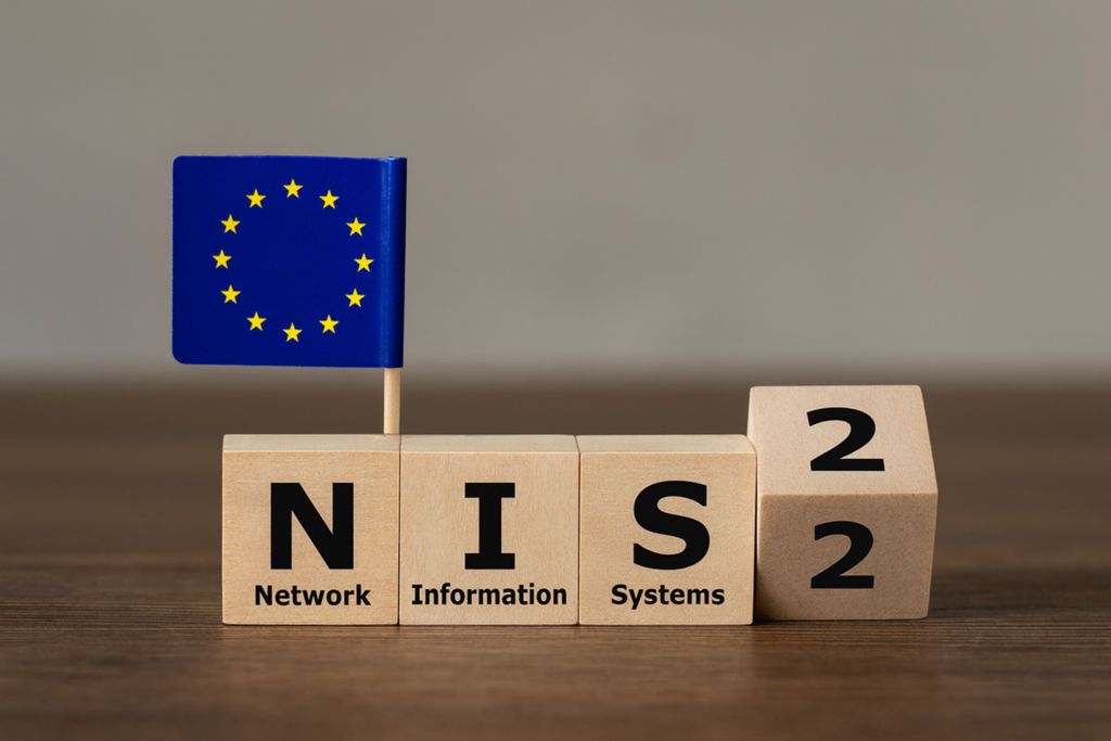 Vier Holzklötzchen auf denen NIS2 geschrieben steht, eine kleine Europafahne steckt im ersten Klotz, eh handelt sich um ein Symbolbild